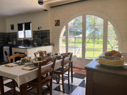 a dining room with a table and chairs and a kitchen at L'Ariade in Monpazier