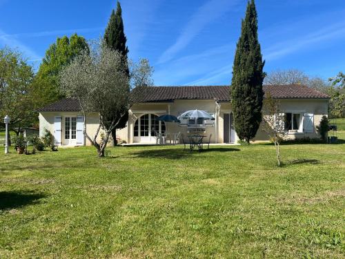 a house with a yard and trees in front of it at L'Ariade in Monpazier