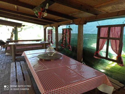 una mesa con un mantel rojo y blanco a cuadros en un porche en Mini-Camp SKELICA en Neštin