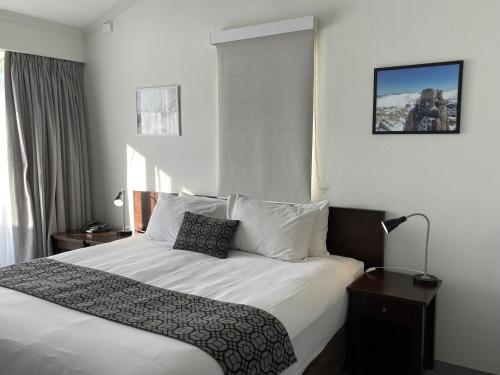 a hotel room with a bed with white sheets and pillows at Horizons 424 Lake Jindabyne Waterfront 2 Bedroom Apartment in Jindabyne