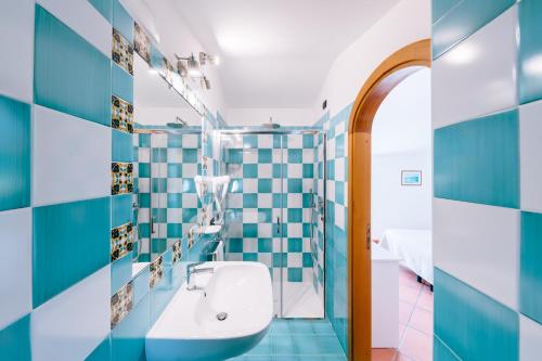 ein Bad mit blau und weiß gefliesten Wänden und einem Waschbecken in der Unterkunft Albergo La Margherita in Scala