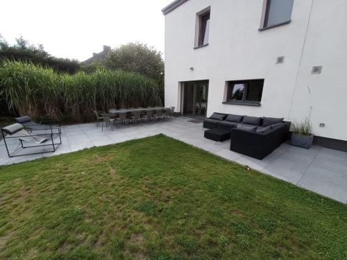 a patio with a couch and tables and a grass yard at Gîte du Lac in Fosses-La-Ville