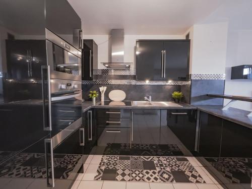 een keuken met zwarte kasten en een wastafel bij TEA&CHILL- Oréo - 2 terraces - 10 min from metro in Bobigny