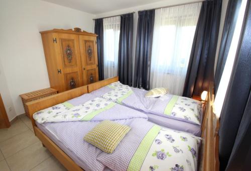 a bedroom with a bed with a wooden frame and curtains at Gästehaus Dürnberg in Pastetten
