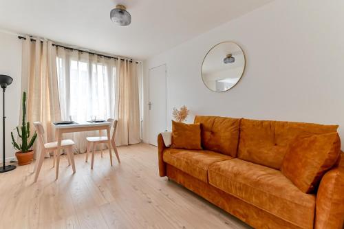 un salon avec un canapé marron et une table dans l'établissement Appartement cosy proche de Paris, à Bagnolet