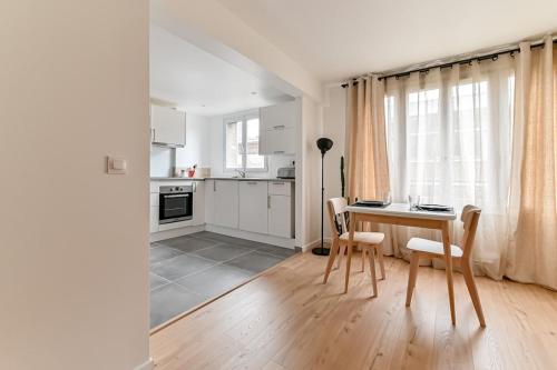 une cuisine avec une table et des chaises dans une pièce dans l'établissement Appartement cosy proche de Paris, à Bagnolet