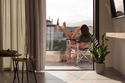 ナフプリオにあるENARIAの窓の外を見下ろす椅子に座る女性