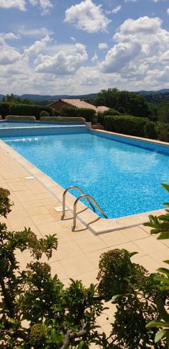 une grande piscine avec de l'eau bleue et des arbres dans l'établissement Petite maison en Ardèche, à Saint-Martin-dʼArdèche