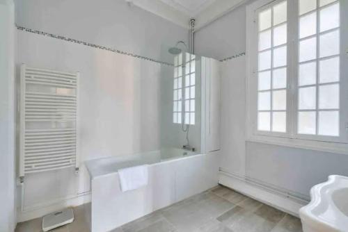 une salle de bain blanche avec une baignoire et un lavabo dans l'établissement Villa La Petite Normandy Vue Mer, à Trouville-sur-Mer