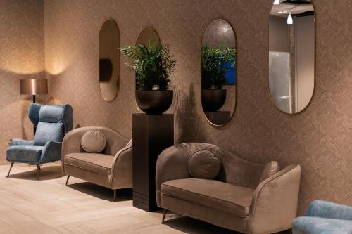una sala de espera con 2 sillas y 2 espejos en Hotel Gerardus, en Szeged