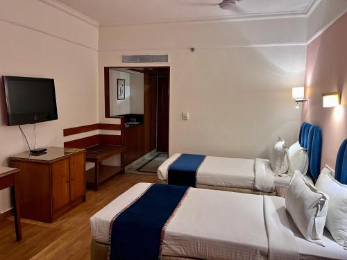 AmeerpetにあるKatriya Hotel and Towerのベッド2台、薄型テレビが備わるホテルルームです。