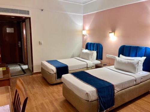 2 łóżka w pokoju hotelowym z niebieskimi zasłonami w obiekcie Katriya Hotel and Tower w mieście Ameerpet