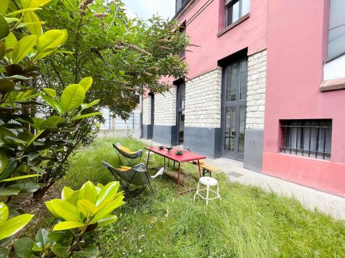 a garden with a red table and chairs in the grass at TEA&CHILL - Nice Triplex Loft - with garden in Montreuil