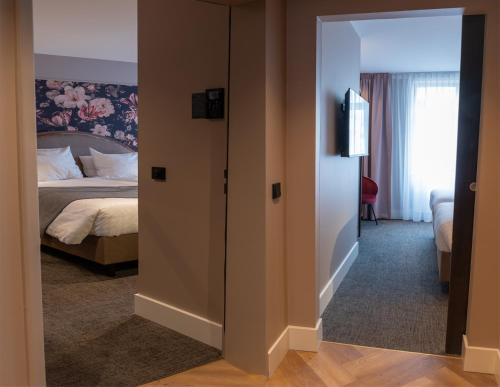 a room with a bedroom with a bed and a mirror at Van der Valk Hotel Hildesheim in Hildesheim
