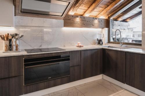une cuisine avec des armoires en bois et un évier dans l'établissement Chalet Mathilda - Les Chalets COVAREL, à Val dʼIsère