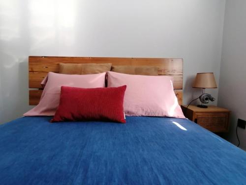 un letto blu con due cuscini rossi sopra di Casa do Favinha a Machico