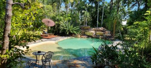 a swimming pool in a garden with a table and chairs at Berry Springs Tropical Retreat in Berry Springs