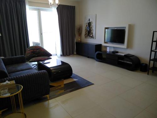 a living room with a couch and a flat screen tv at Sifah Inn in As Sīfah