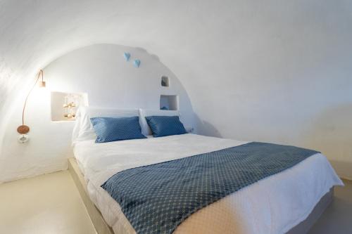 a white bedroom with a bed with blue pillows at Trulli Tower in Putignano