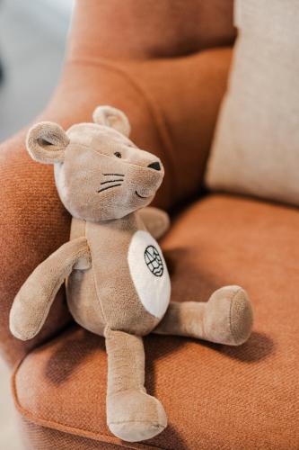 a teddy bear sitting on a couch at NOI Resort SPA - woda i las in Tęgoborze