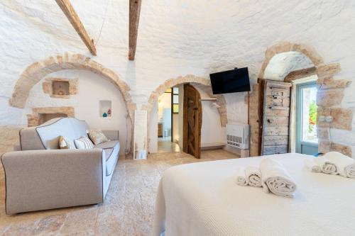 a bedroom with two beds and a couch and a tv at Trulli Tower in Putignano