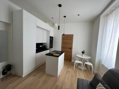- une cuisine avec des placards blancs et une table dans une pièce dans l'établissement Appartement cosy à 1 min de Paris, à Charenton-le-Pont