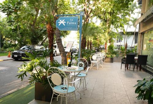 La Palma - Garden Saigon Hotel Phu My Hung في مدينة هوشي منه: طاولة وكراسي على رصيف جانبي بجانب شارع