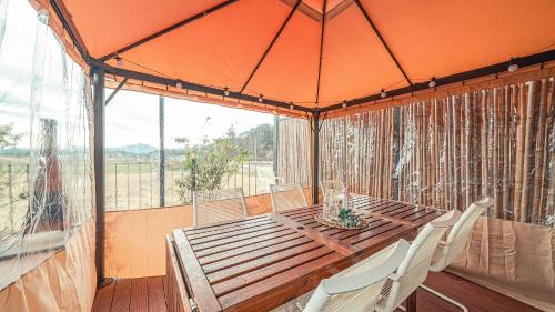 a wooden table with white chairs and an orange umbrella at Majoong Pool Villa Pension in Gyeongju