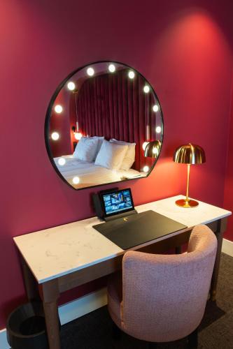 a bedroom with a bed with a mirror above a desk at Van der Valk Hotel Hildesheim in Hildesheim