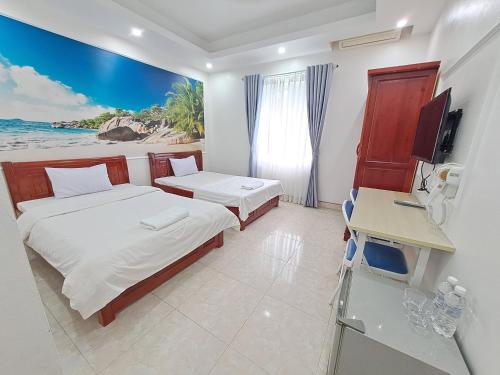 a bedroom with two beds and a desk with a computer at HTC Hotel Tuần Châu Island in Ha Long
