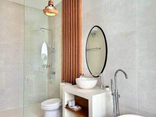 a bathroom with a sink and a toilet and a mirror at Tujuan Jogja Villas - Bima With Private Pool in Jetis