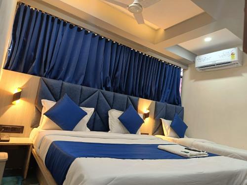 1 dormitorio con 1 cama grande y cortinas azules en hotel shivkunj, en Ahmedabad