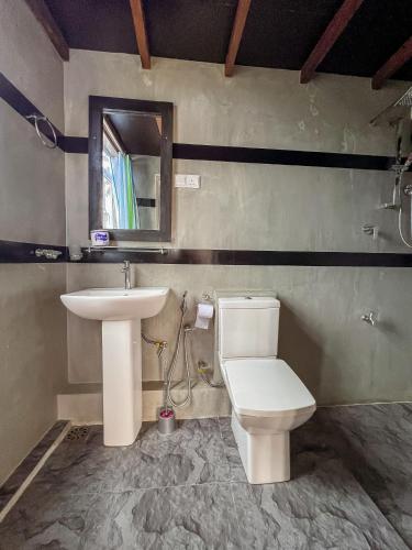 a bathroom with a sink and a toilet and a mirror at Light House View Inn - Galle Fort in Galle