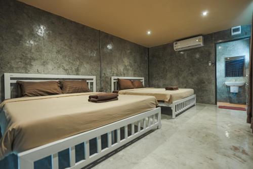 a bedroom with two beds and a sink at Phuniphat Pool Villa in Nong Prue