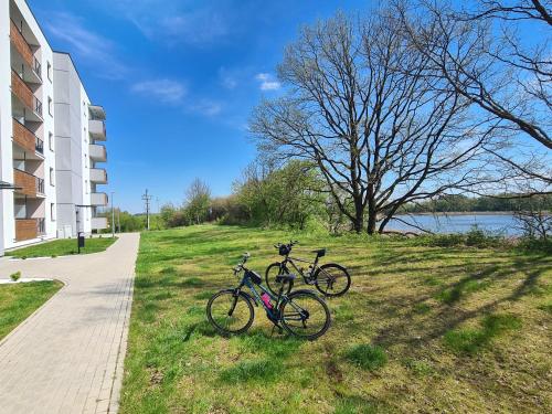 dos bicicletas estacionadas en el césped junto a un edificio en Przystań Natura, en Iława