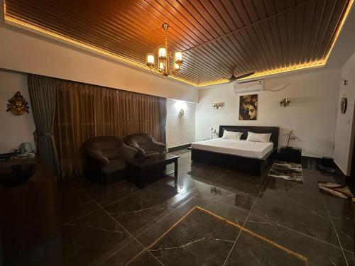 um quarto com uma cama, uma cadeira e um lustre em YKC FARMS em Bāghdogra