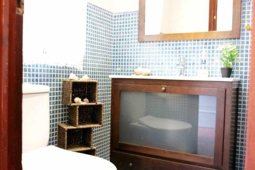 a bathroom with a tv and a blue tiled wall at Nahe Meer - Sonne pur - verkehrsfrei in Cala del Moral