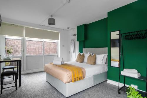 Livestay Affordable En-Suite Studio Rooms in London, N14 في East Barnet: غرفة نوم خضراء وبيضاء مع سرير ومكتب