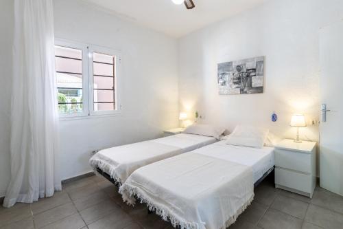 two beds in a white room with two windows at Can Pep Ramon 2 in Sant Francesc de s'Estany