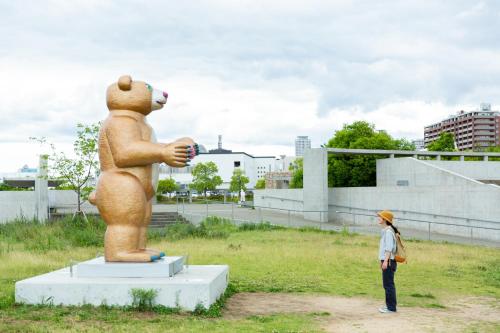 a woman standing next to a large teddy bear statue at Kobe Guesthouse MAYA in Kobe