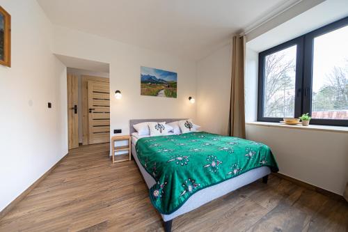 um quarto com uma cama com um cobertor verde em Apartamenty GoMiś Zakopane em Zakopane