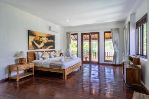 a bedroom with a bed and a table and windows at Villa Aveli Seminyak by Best Deals Asia Hospitality in Seminyak