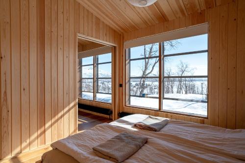 a bedroom with wooden walls and a bed with two windows at Kalamaja Kilpisjärvi in Kilpisjärvi