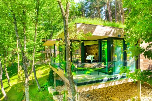 una casa nel bosco con una facciata in vetro di Bioli Wellness Resort a Kojori
