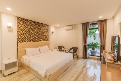 a bedroom with a bed and a television and a table at Top Pool Villa B5 in Pattaya Central