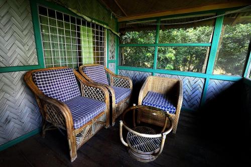 a porch with three chairs and two windows at Jayanta Hotel in Chittagong
