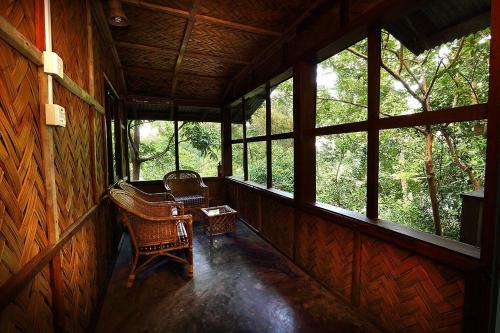 a porch of a cabin with two chairs and windows at Jayanta Hotel in Chittagong