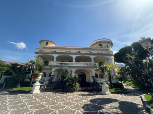 a large white building with stairs and palm trees at Villa Le Zagare Relais & SPA in Gragnano