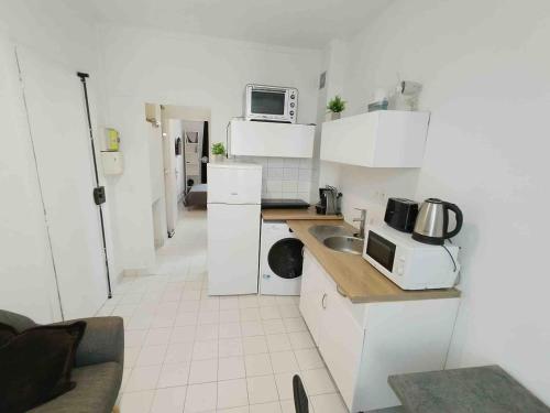a small kitchen with white cabinets and a microwave at Cozy Polo's House in Bagnolet