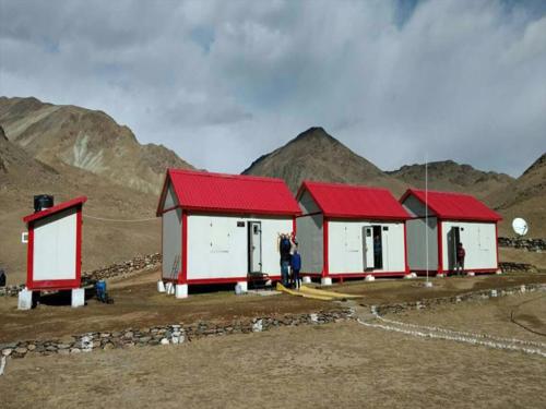 a row of red and white buildings with mountains in the background at Containers house in Meerut